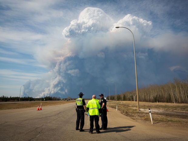 Officers look on as smoke from Fort McMurray's raging wildfire billow into the air after their city was evacuated.