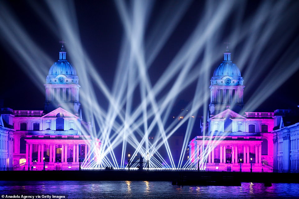 Lights shine up into the sky during a midnight display of drones and fireworks celebrating the new year at the Old Royal Naval College at Greenwich in London